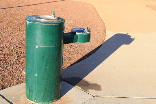 Bi-level green outdoor pedestal-style drinking fountain situated in a recreational area of Paseo Highlands park in northern Phoenix, Arizona