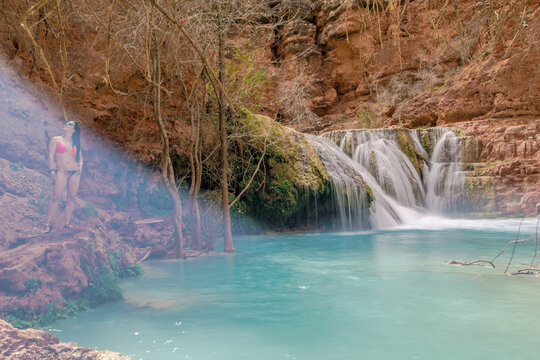 A woman is standing in front of a waterfall