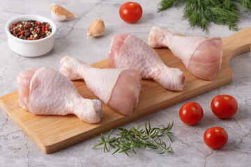 Fresh chicken drumsticks and vegetables on a cutting board in a kitchen setting ready for cooking