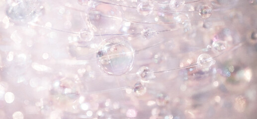 Transparent bubbles suspended in a delicate web of fine threads, creating an ethereal effect against a soft, blurred background of light colors