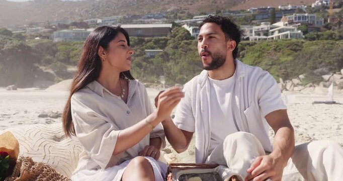 Feeding, food and picnic with couple on beach together for anniversary, date or romance. Bite, fork and sharing with happy people eating outdoor on coast for holiday, travel or vacation in summer