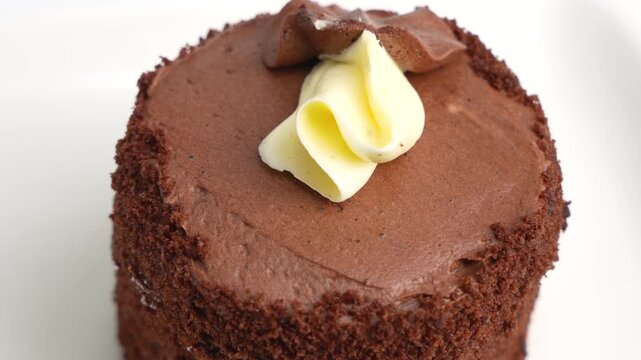 A rich chocolate cake with layered frosting rotates slowly for a detailed view. The spinning dessert is filmed on a clean white background.