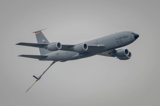 A KC135 aerial refueling jet flies by with boom extended
