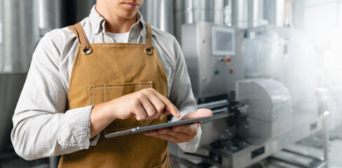 Owner brewer using tablet in modern craft brewery for efficient production management, banner