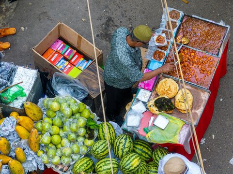 Dhaka, Bangladesh - 01 March 2026: Aerial view of a vibrant street food vendor in Chawkbazar, showcasing colourful fruits, savory dishes, and freshly baked bread.