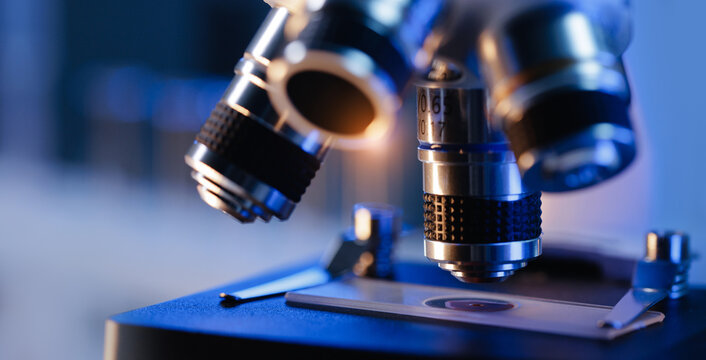 Close-up of microscope lenses focusing on slide in laboratory setting