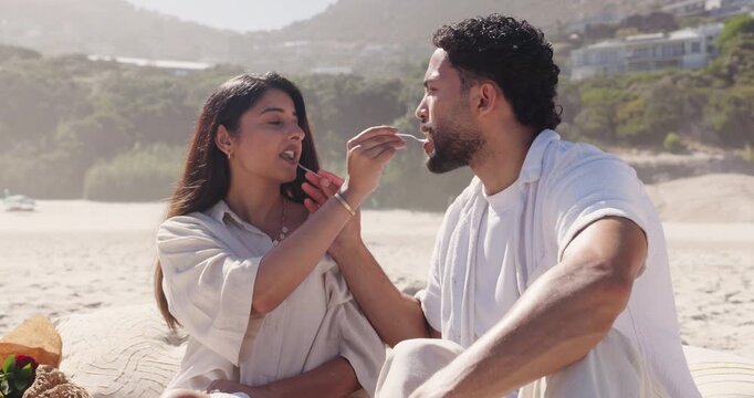 Bite, feeding and picnic with couple on beach together for anniversary, date or romance. Food, fork and sharing with happy people eating outdoor on coast for holiday, travel or vacation in summer