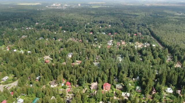 Drone flying forward descending over forest village