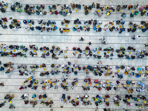 Dhaka, Bangladesh - 03 March 2026: Aerial view of orderly rows of people gathered outside the National Mosque, their colorful clothes creating a vibrant mosaic against the stark white ground.