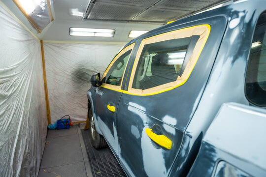 Automotive service painting a vehicle in spray booth