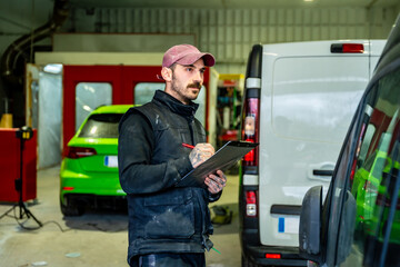 Fototapeta premium Mechanic inspecting van and car body in a paint shop