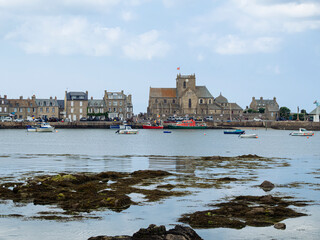 Vistas de la Iglesia San Nicolás del pueblo de Barfleur  paisaje de costa de la Normandía francesa, sobre cielo azul con nubes y reflejos en el mar, viajando en verano de 2022 © acaballero67