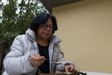 Woman having an outdoor lunch, casually eating traditional food from a plantain leaf wrapper with a spoon, enjoying a moment of simplicity and comfort © Rangel
