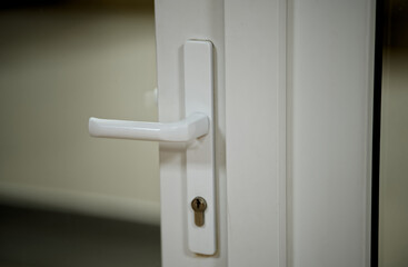 Vertical view of a closed plastic door with a white latch and keyhole. Selective focus on the locking mechanism. Concept of home safety, privacy, and interior design. Photo