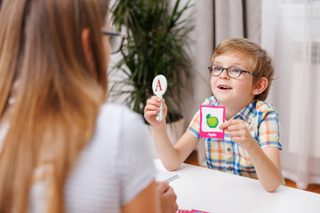 Young boy learning with flashcards at a table with a woman