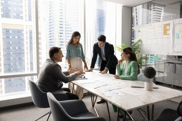 Multiethnic company managers startup developers team with middle aged leader boss gather around boardroom table brainstorming insights creating plans reviewing project materials in modern urban office © fizkes
