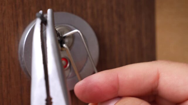 Close up of a hand inserting and turning a metal key in a door lock cylinder on a wooden door, shallow depth of field showing silver hardware, keyhole detail, and secure home entry access indoors