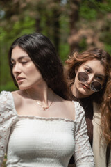 Obraz premium Two attractive and elegant young women models portrait outdoors on a sunny spring day in the forest