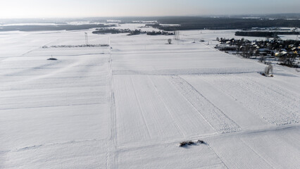 Aerial view of a vast snow-covered landscape under a clear sky, showcasing patterns in the white snow. The scene represents winter tranquility and natural beauty, ideal for seasonal themes.