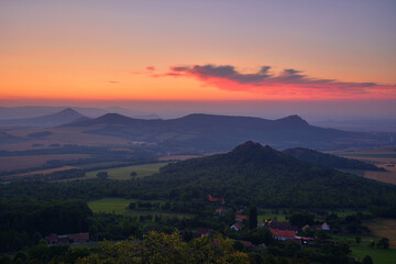 Obraz premium Vibrant Red Dawn over Bohemian Hills and Small Village