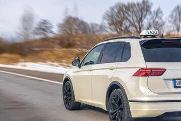 Naklejka premium White taxi crossover driving on winter road. Urban transport service in motion.