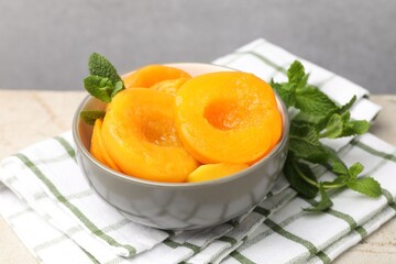 Pickled peaches and mint leaves in bowl on light grey table, closeup © New Africa