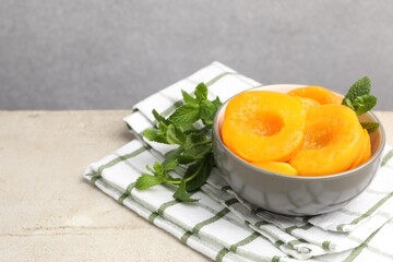 Pickled peaches and mint leaves in bowl on light grey table, closeup. Space for text © New Africa