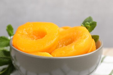 Pickled peaches and mint leaves in bowl on table, closeup © New Africa