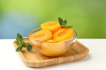 Pickled peaches and mint leaves in bowl on white wooden table, closeup © New Africa