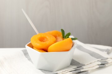 Pickled peaches and mint leaves in bowl on white table, closeup © New Africa