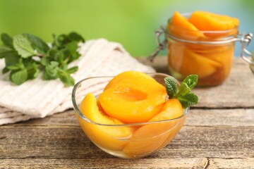 Pickled peaches and mint leaves on wooden table, closeup © New Africa