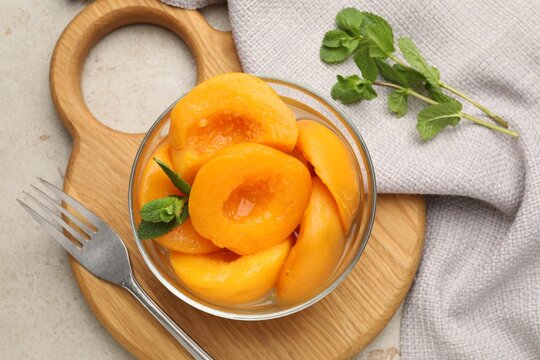 Pickled peaches and mint leaves in bowl on light grey table, flat lay