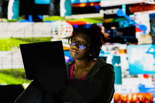 Woman addicted to watching internet clips, unable to stop using notebook. African american person with tired eyes staring at laptop screen, concept of technology overuse and digital dependence