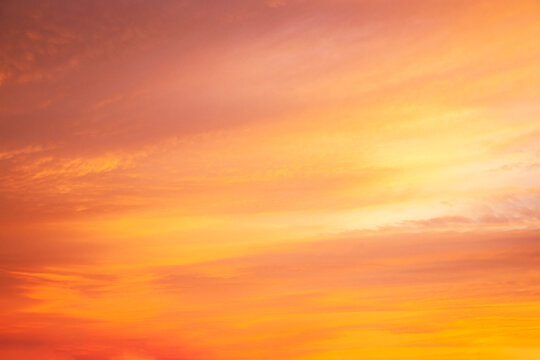 A winter sunrise sky painted with clouds colored orange, yellow, pink and purple, creating a dramatic scene just before the sun rises at dawn.