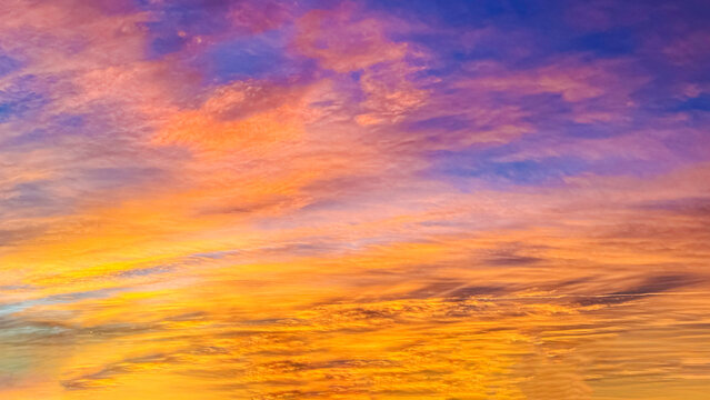 Dramatic soft lavender and golden sunrise clouds with warm pastel gradient clouds, fill the sky at sunrise, making for a colorful dawn to a new day.
