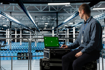 Data center employee using green screen notebook, minimizing downtime through predictive...