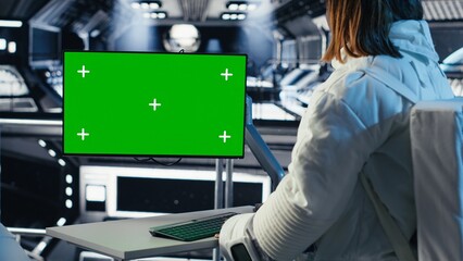 Fototapeta premium Astronaut reviewing onboard analytics on green screen monitor before stepping outside space station. Cosmonaut verifying parameters on mockup display after landing on planet