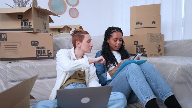 Lesbian couple planning relocation together surrounded by moving boxes