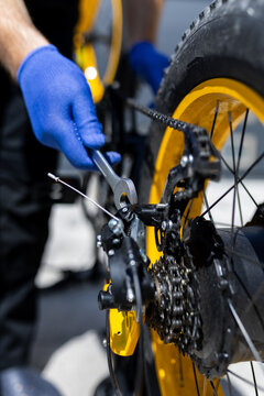 Bike repair done with tools on a yellow bicycle in a workshop setting during the day