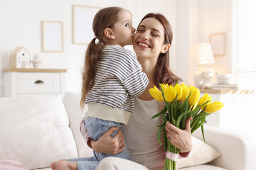 Happy Mother's Day. Little girl and her mom with beautiful tulips on sofa indoors © New Africa