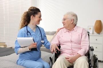 Obraz premium Care worker supporting senior woman in wheelchair indoors