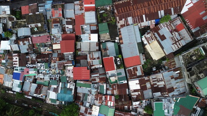 Aerial top-down view of dense urban informal settlement with rusted metal roofs beside a railway track © Christian