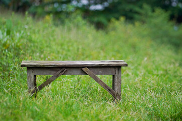 Old Weathered Wooden Bench in Lush Green Meadow with Bokeh Background