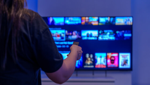 Person using remote to browse streaming apps on smart tv