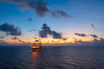 Aerial view of offshore jack up rig and offshore platform during sunset for oil and gas exploration and production.
