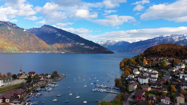 Spiez village aerial view with deep blue Lake Thun autumn trees and majestic Niesen mountain. Spiez, Canton of Bern, Switzerland.