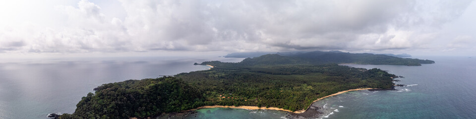 Fototapeta premium An aerial panorama of the lush tropical coastline, sandy beaches, and coral reefs of southern São Tomé Island, São Tomé and Príncipe.
