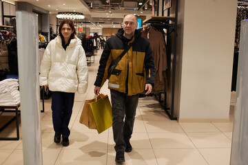 Fototapeta premium A man and a woman leave a clothing store with shopping bags