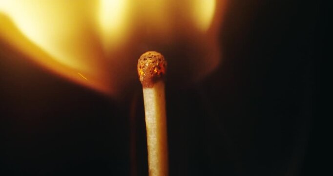 Igniting match against black background. Cinematic footage in slow motion, macro shot