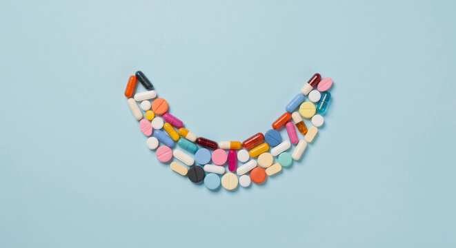 Creative Flat Lay of Vitamin Pills Forming a Smile on Blue Background